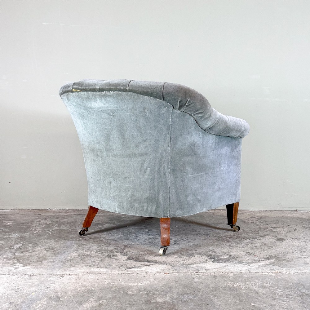 A Victorian-style grey velvet tub armchair featuring deep button tufting on the curved backrest, rolled arms, and tapered wooden legs on casters. View IV
