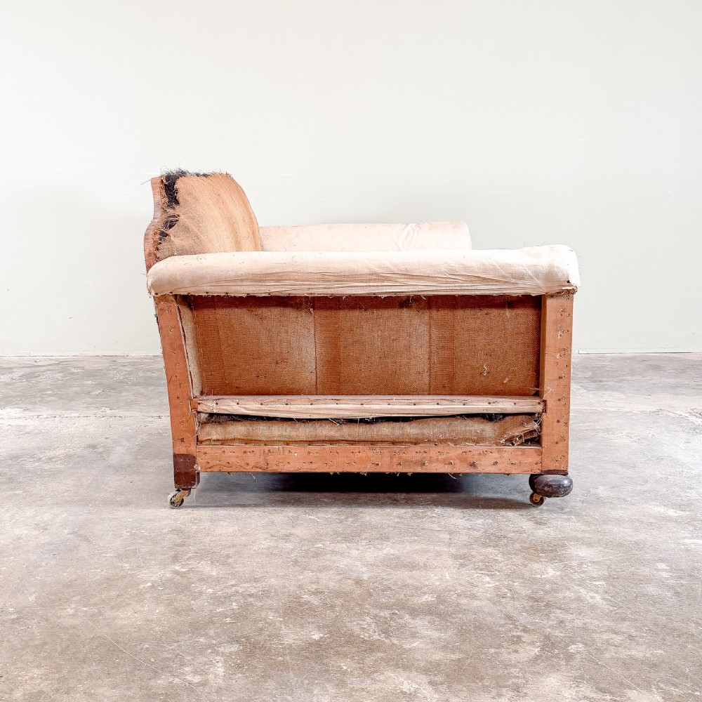 A 1930s deep-seated country house sofa frame upholstered in natural hessian and calico with turned wooden feet on brass castors. View III
