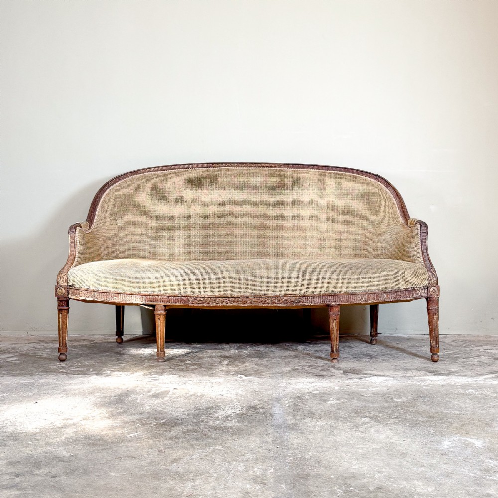 A mid-19th century French canape featuring a carved wooden frame with fluted legs and warm beige upholstery. View II