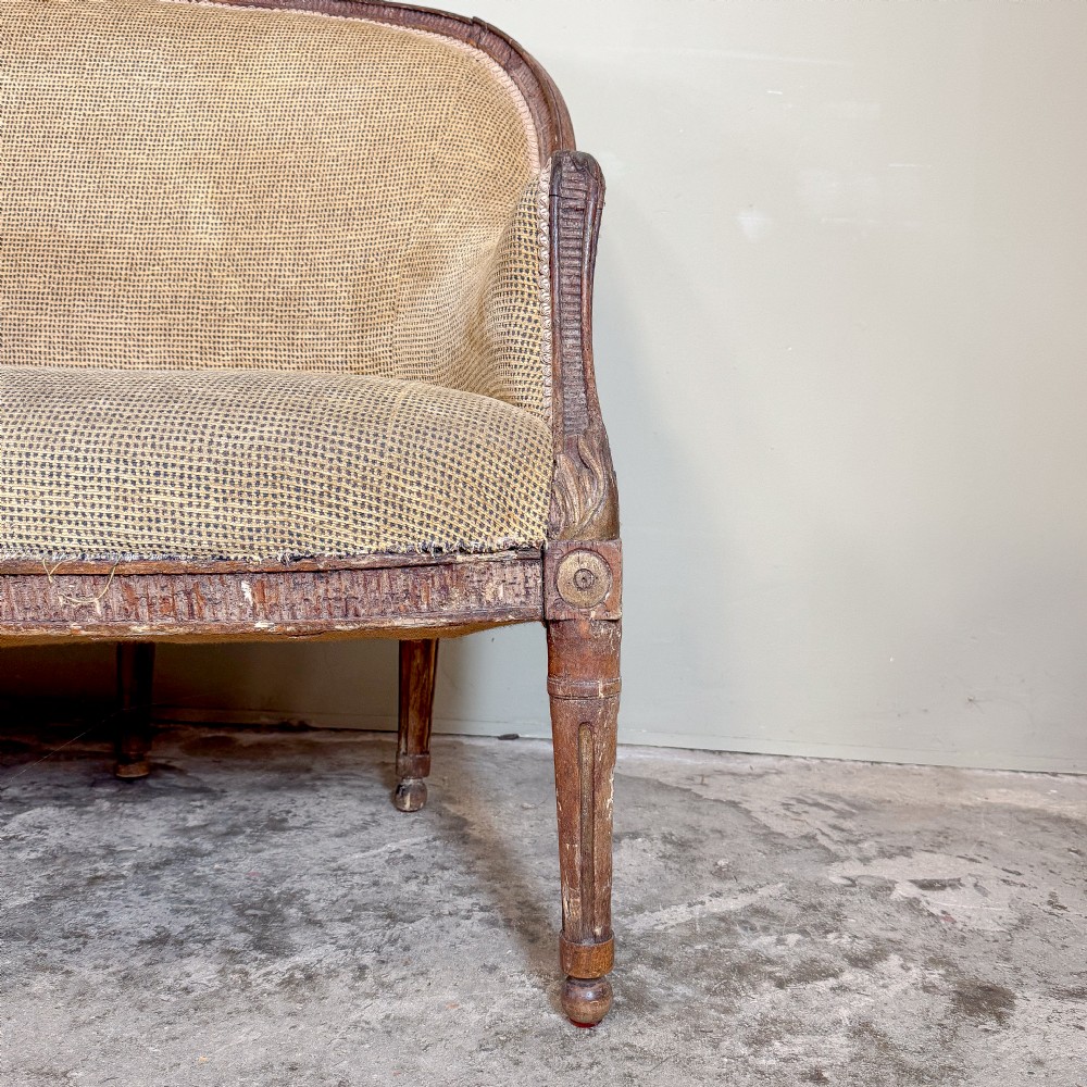 A mid-19th century French canape featuring a carved wooden frame with fluted legs and warm beige upholstery. View V