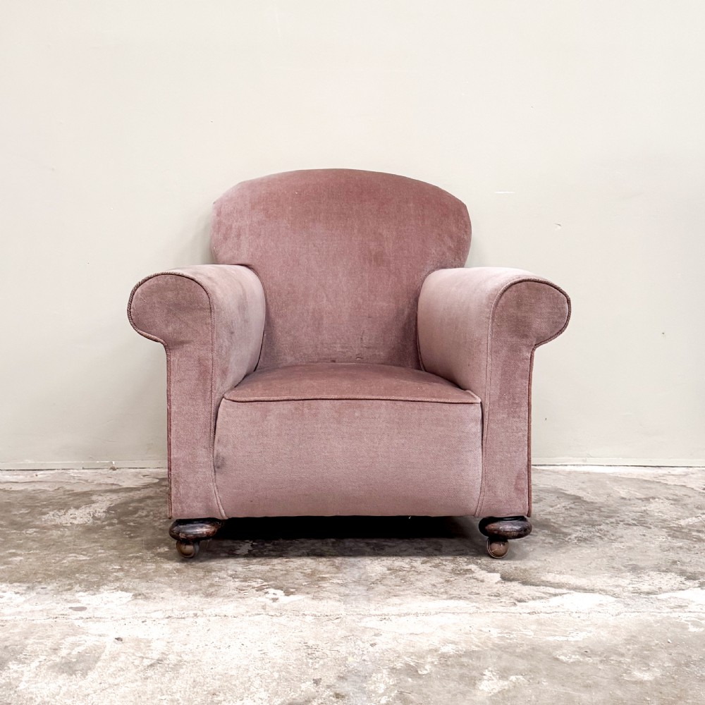 A 1930s upholstered armchair covered in dusty pink velvet with a curved back, rolled arms, and turned feet on castors. View II