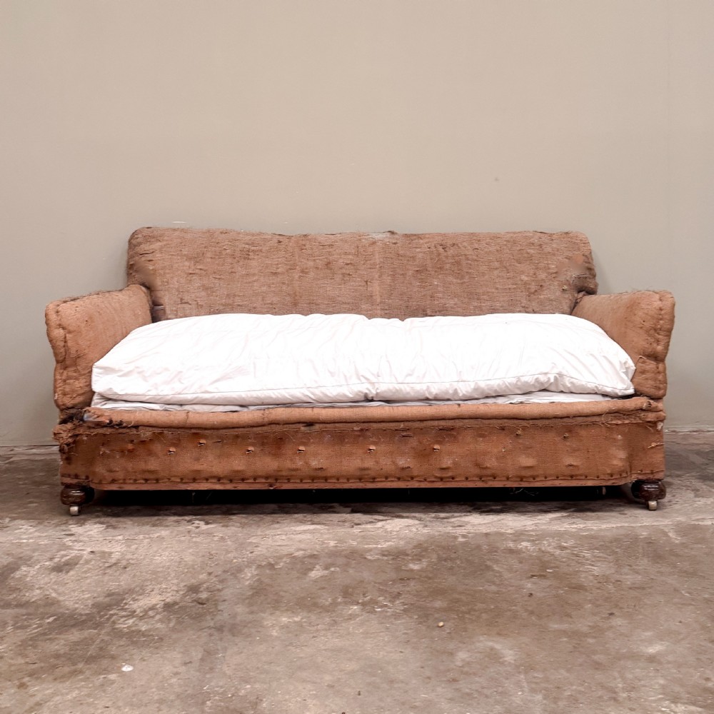 A 1930s three-seater sofa frame stripped down to its natural hessian lining with turned timber front legs on brass castors. View II