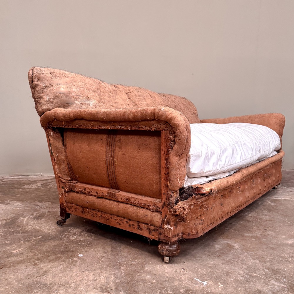 A 1930s three-seater sofa frame stripped down to its natural hessian lining with turned timber front legs on brass castors. View III