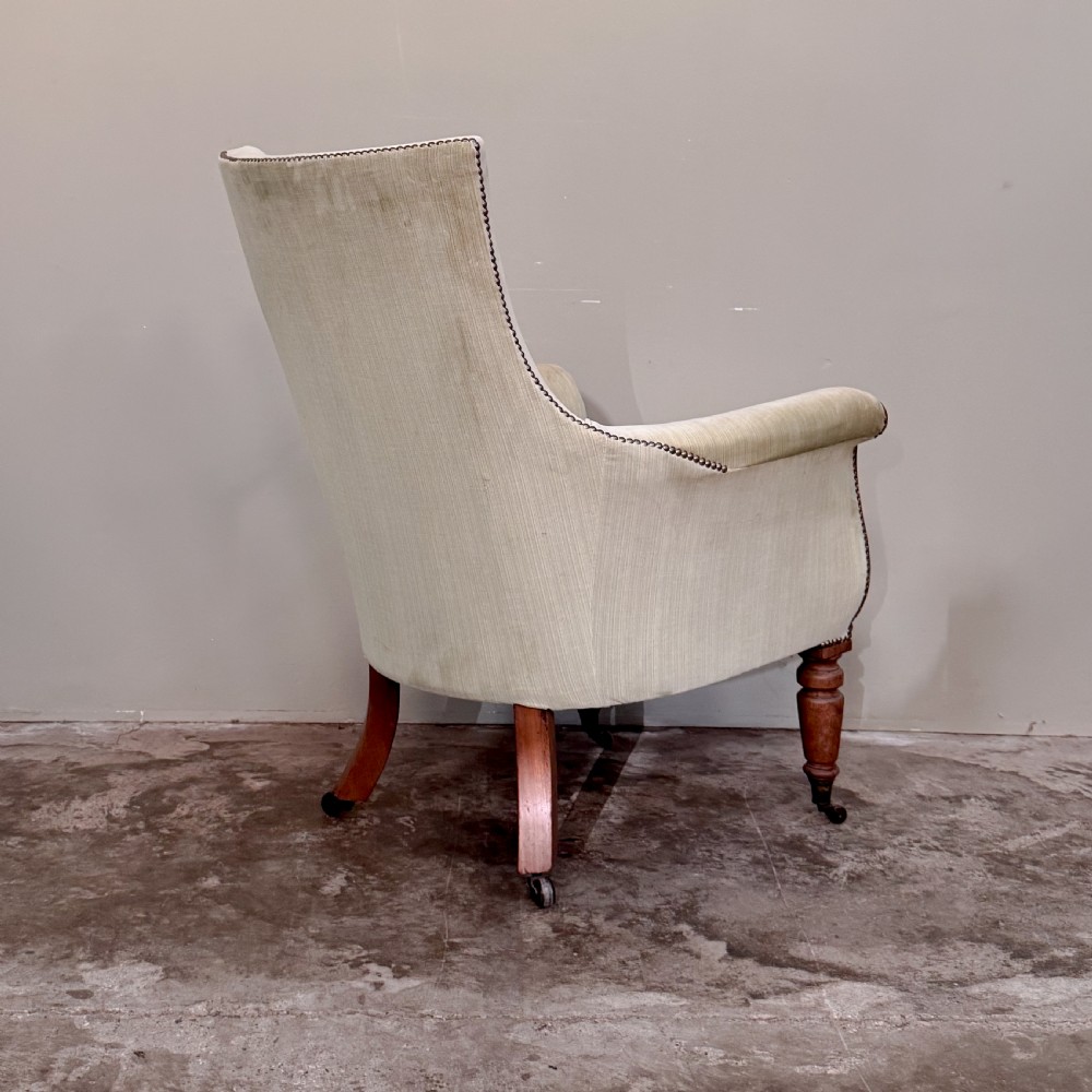 A Regency period library armchair upholstered in pale green velvet, featuring carved mahogany lyre-shaped arms and turned front legs on brass castors. View IV
