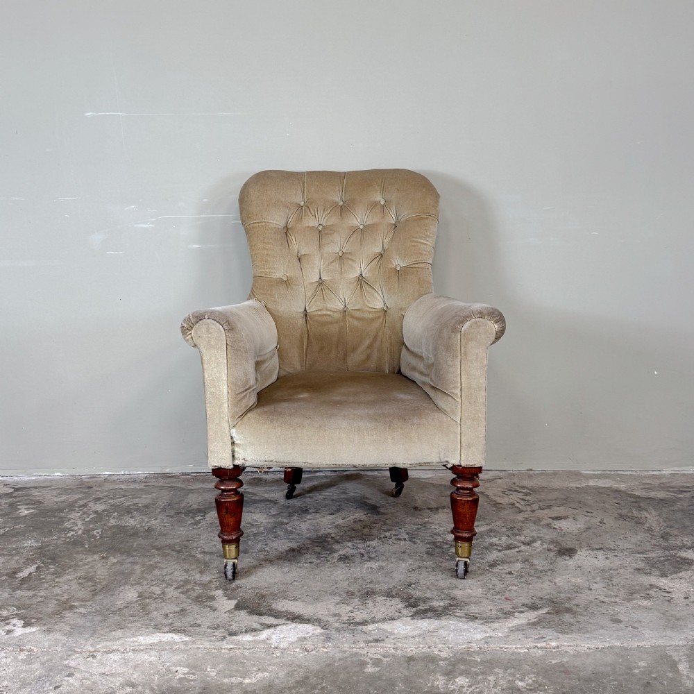 A nineteenth-century Victorian library armchair upholstered in beige velvet featuring a button-tufted backrest and turned mahogany legs with brass castors. View II