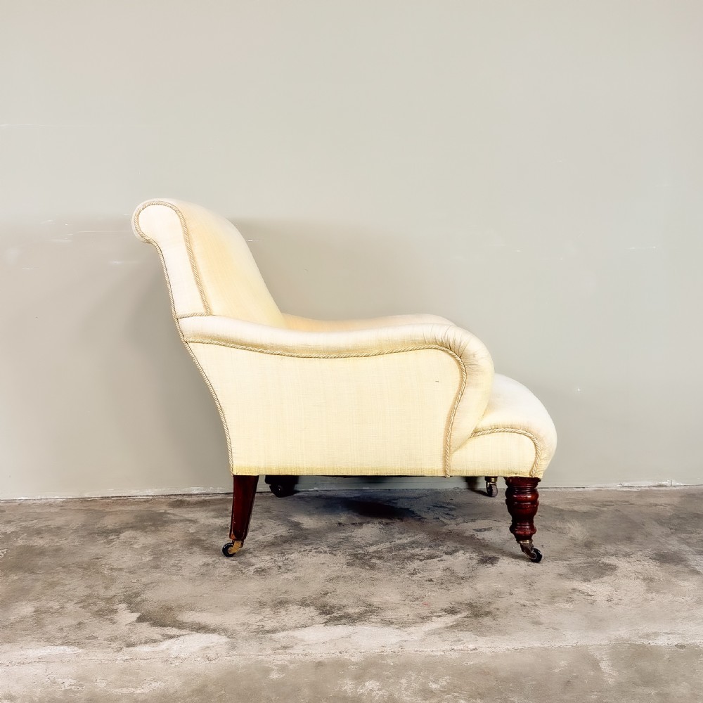 A 19th-century upholstered armchair featuring pale yellow fabric, padded P-shaped arms, and dark turned mahogany legs on brass castors. View III