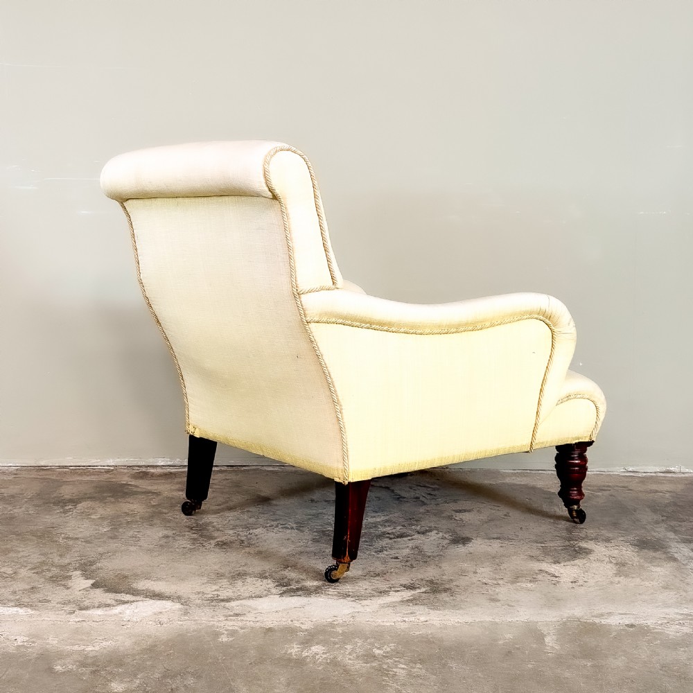 A 19th-century upholstered armchair featuring pale yellow fabric, padded P-shaped arms, and dark turned mahogany legs on brass castors. View IV