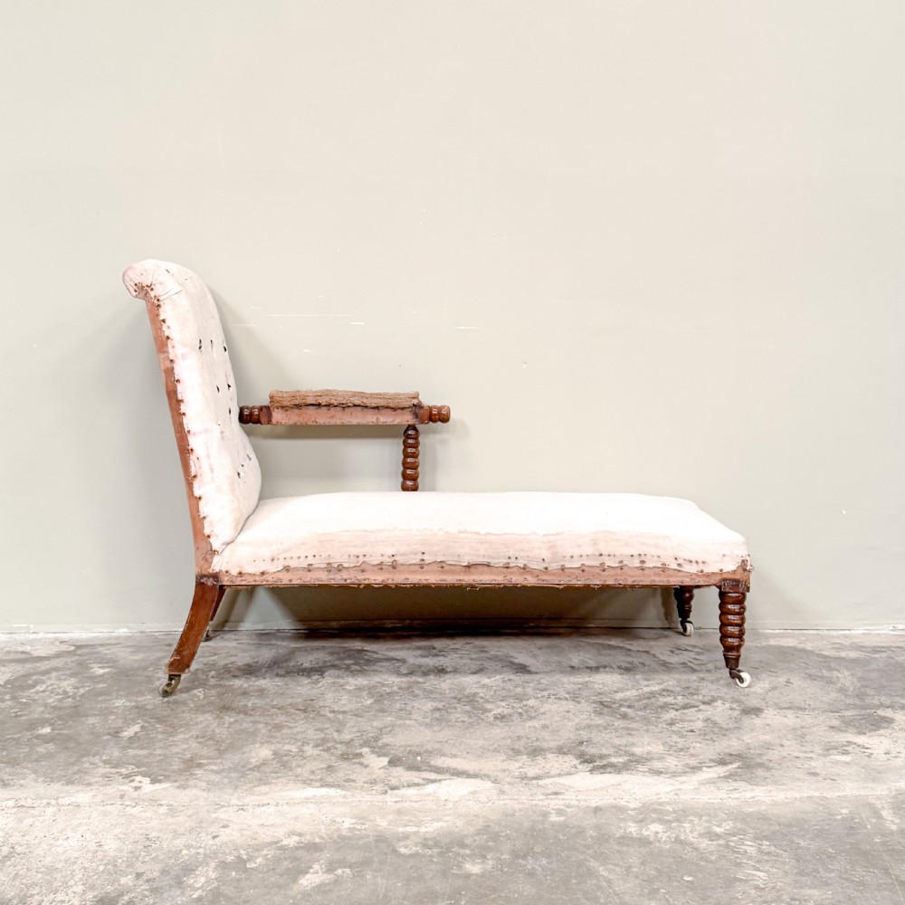 A 19th-century Victorian bobbin day bed featuring a single upholstered arm, button-tufted backrest, dark bobbin-turned legs, and castors. View IV