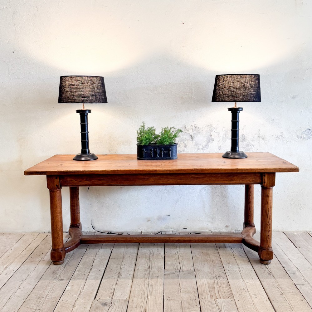 A rectangular solid oak refectory dining table featuring a plank top, barrel-turned legs, and a low central H-stretcher base. View II