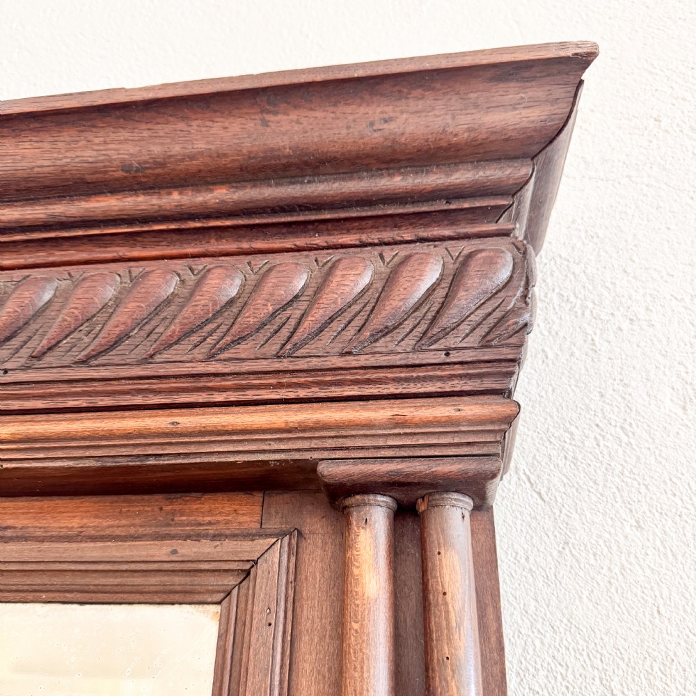 A tall Victorian carved walnut overmantel mirror featuring an architectural cornice, fluted side columns, and an embellished upper frieze. View III