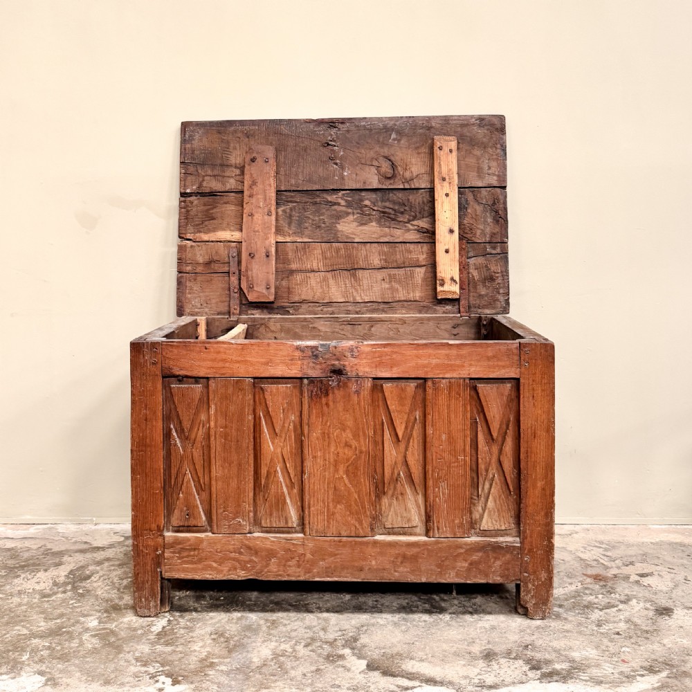 An 18th-century French provincial wooden coffer featuring hand-carved geometric front panels and a hinged top lid. View V