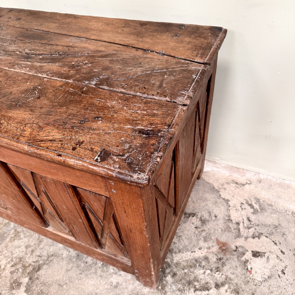 An 18th-century French provincial wooden coffer featuring hand-carved geometric front panels and a hinged top lid. View VI