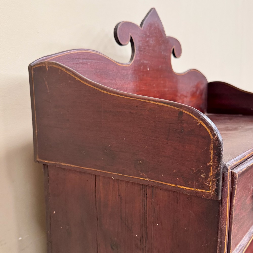 An antique dark reddish-brown painted wooden open bookcase featuring a shaped pediment backboard, a single top drawer with wooden knobs, and four open shelves on turned bun feet. View V