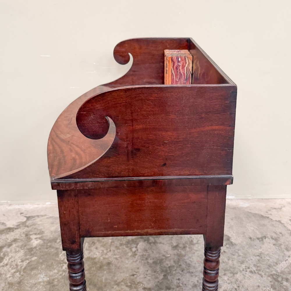 A Regency mahogany washstand featuring a raised scroll-shaped splashback gallery, two frieze drawers with round brass knobs, and four slender turned legs. View V