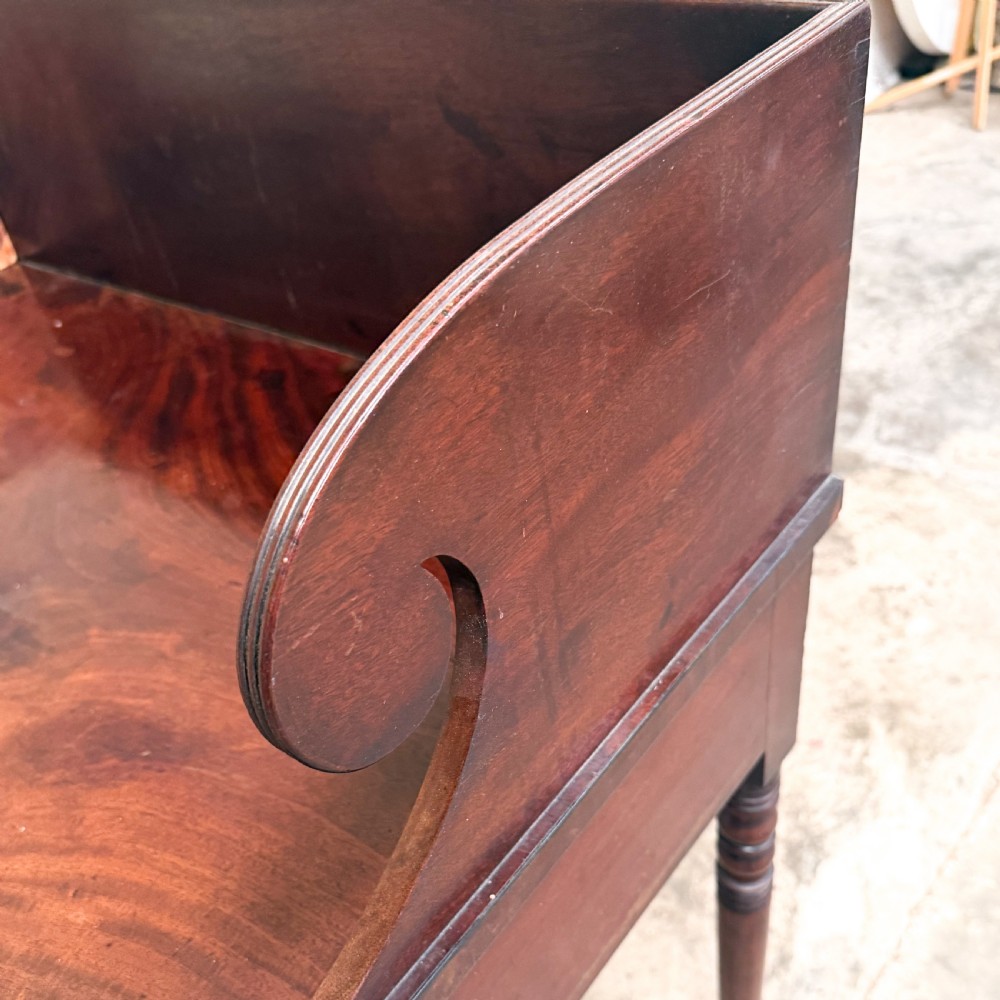 A Regency mahogany washstand featuring a raised scroll-shaped splashback gallery, two frieze drawers with round brass knobs, and four slender turned legs. View VII