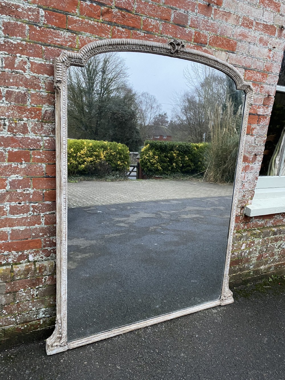 A large 19th-century arched overmantel mirror with a painted off-white ribbed gesso frame displaying mild distressing. View VII