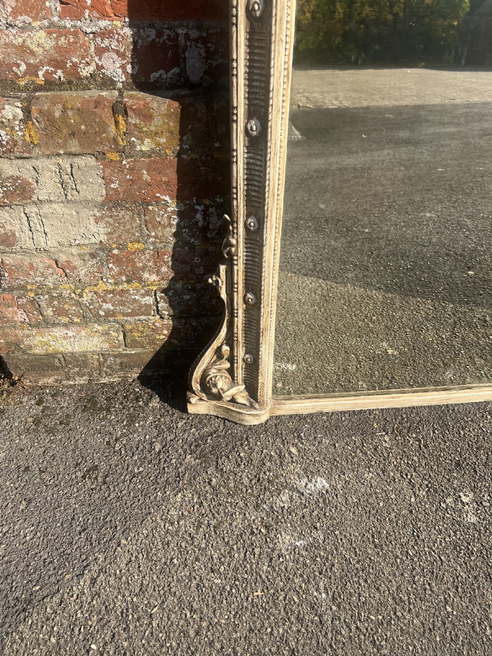 A large 19th-century painted overmantel mirror featuring an arched top decorated with a carved leaf cresting and distressed cream finish. View III