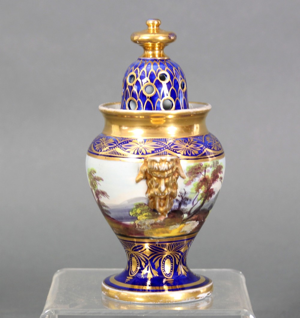 An antique Masons ironstone potpourri urn decorated with cobalt blue and gold motifs, featuring a hand-painted landscape panel, mask handles, and a pierced dome lid. View II