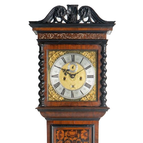 fig 1. An antique late 17th-century floral marquetry longcase clock featuring a square brass dial, barley-twist hood columns, and intricate inlaid panels.