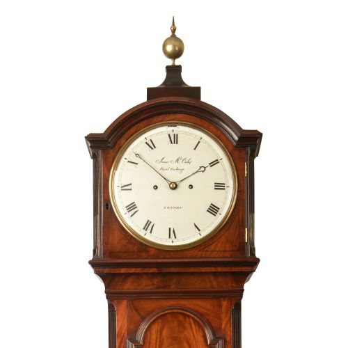 fig 1. A tall Georgian flame mahogany longcase clock featuring an arched hood with a brass ball finial, a white enamel dial signed James McCabe London, and a moulded trunk door.
