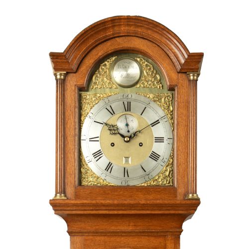 fig 1. An 18th-century Georgian oak longcase clock featuring a brass dial with corner spandrels and an arched hood.