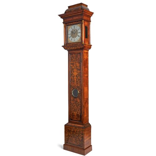fig 1. An antique walnut longcase clock featuring floral marquetry inlays, a square brass dial with a silvered chapter ring, and a glass lenticle set into the trunk door.