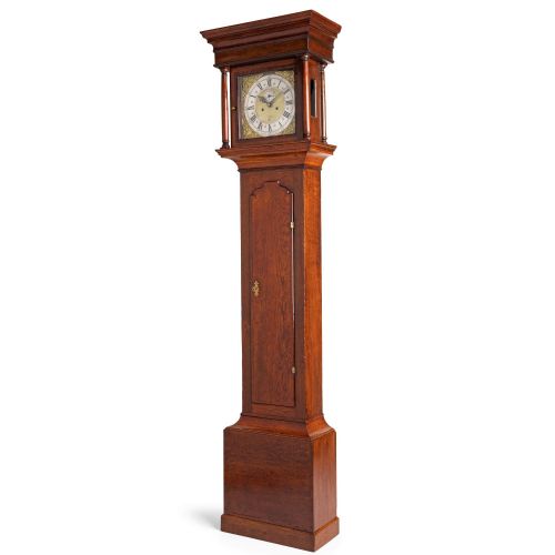fig 2. An antique Georgian oak longcase clock featuring a square brass dial with Roman numerals and turned hood columns.