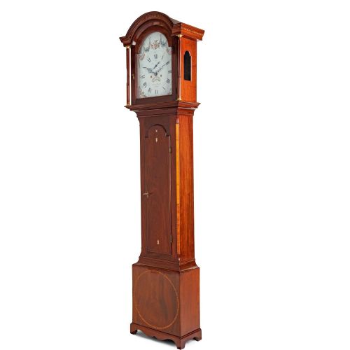 fig 2. An antique mahogany Channel Island longcase clock featuring a painted arched dial with floral detail, an inlaid waist door, and turned hood columns.