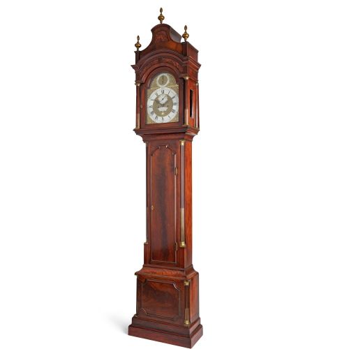 fig 2. A Georgian flame mahogany longcase clock featuring an arched brass dial with brass finials on a shaped hood.