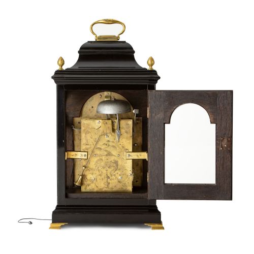 fig 2. An 18th-century style ebonised bracket clock featuring a bell top case with a brass handle, pinecone finials, and a silvered brass dial with decorative spandrels.