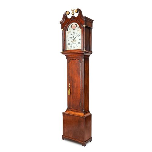 fig 1. A tall dark oak longcase clock featuring a swan-neck pediment, brass eagle finial, arched painted dial with moonphase movement, and a central trunk door.