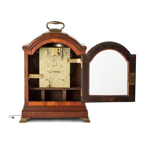 fig 2. An arched Regency mahogany bracket clock featuring a circular dial signed Thwaites and Reed London, framed by a brass bezel and brass fish-scale fretwork with red backing.