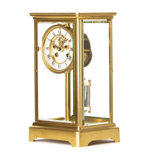 fig 1. A rectangular brass and bevelled glass French four-glass clock featuring a white enamel dial with Roman numerals and a visible pendulum.