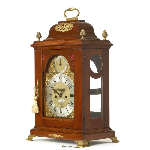 fig 2. A Georgian mahogany bracket clock with a brass carrying handle, pinecone finials, and an arched brass dial signed Robert Higgs London.