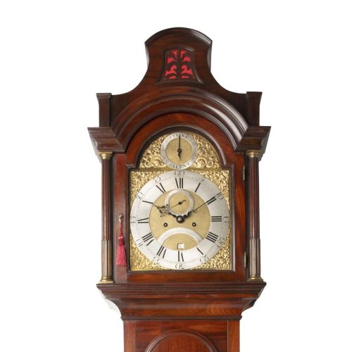 fig 1. A tall Georgian mahogany longcase clock featuring a pagoda hood, brass decorative spandrels, a silvered dial, and a polished wooden case.