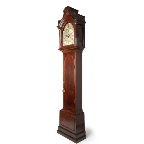 fig 2. A tall Georgian mahogany longcase clock featuring a pagoda hood, brass decorative spandrels, a silvered dial, and a polished wooden case.
