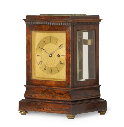fig 1. An early nineteenth-century rosewood five-glass library timepiece featuring an engine-turned brass dial with Roman numerals and a stepped plinth base.