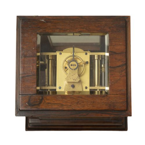 fig 2. An early nineteenth-century rosewood five-glass library timepiece featuring an engine-turned brass dial with Roman numerals and a stepped plinth base.