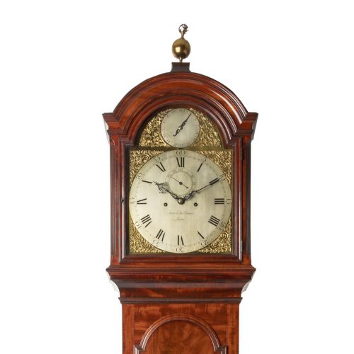 fig 1. An eighteenth-century Georgian mahogany eight-day longcase clock featuring an arched hood with a brass finial and a flame mahogany veneer trunk door.