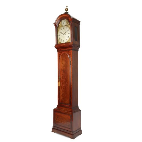 fig 2. An eighteenth-century Georgian mahogany eight-day longcase clock featuring an arched hood with a brass finial and a flame mahogany veneer trunk door.