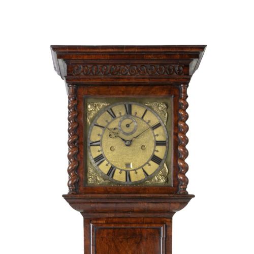 fig 1. A slender late 17th-century walnut longcase clock featuring a square brass dial, barley twist hood columns, and rich figure-grained timber.
