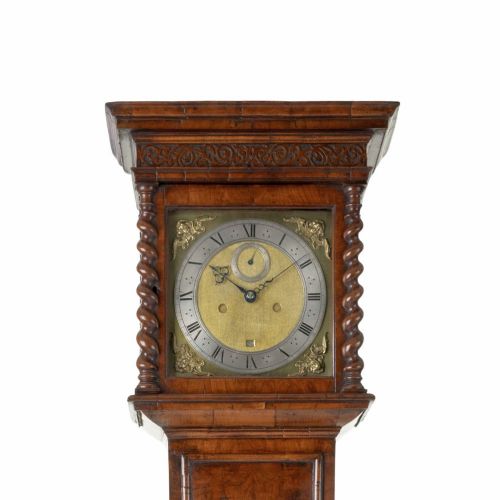fig 1. A 17th-century walnut longcase clock featuring a square brass dial, barley-twist columns on the hood, and a slender veneered trunk set upon a plinth base.