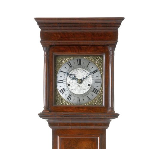 fig 1. A miniature longcase clock crafted from figurative walnut veneer featuring a brass dial with Roman numerals and a plinth base.