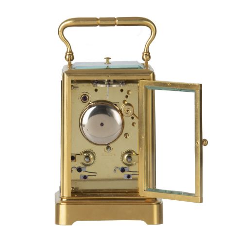 fig 1. A rectangular brass repeating carriage clock featuring a top carrying handle, glass side panels, and a white enamel dial with black Roman numerals.
