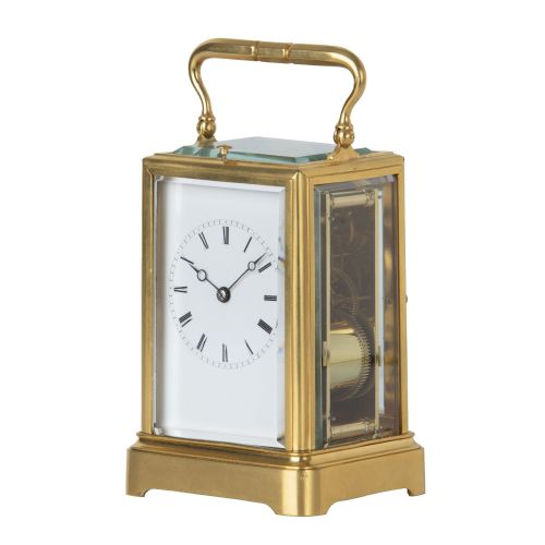 fig 2. A rectangular brass repeating carriage clock featuring a top carrying handle, glass side panels, and a white enamel dial with black Roman numerals.