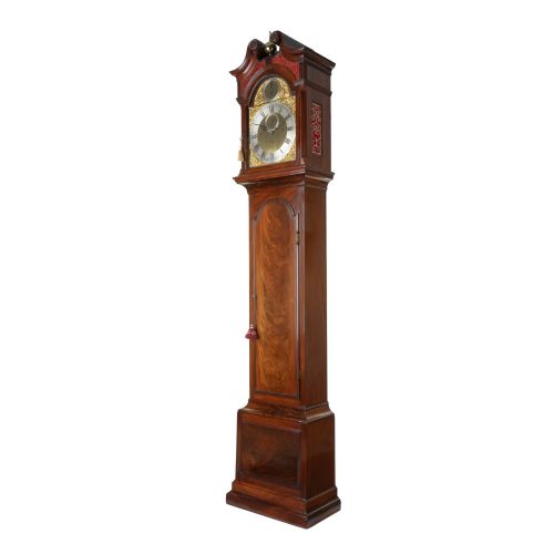 fig 2. An 18th-century Georgian mahogany longcase clock featuring an arched hood with a brass finial, a gilded brass dial, and a flame mahogany trunk door.