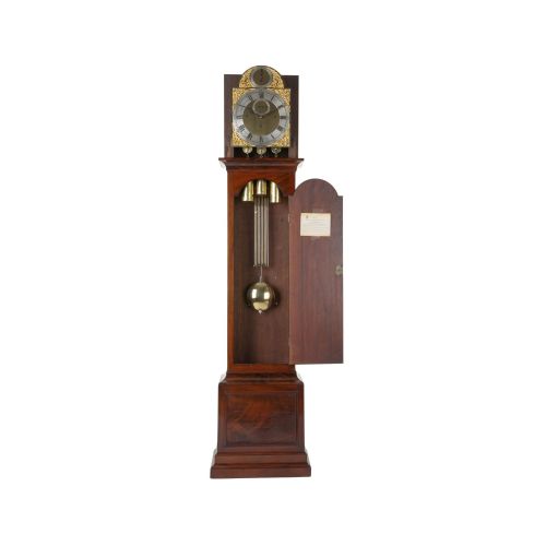 fig 3. An 18th-century Georgian mahogany longcase clock featuring an arched hood with a brass finial, a gilded brass dial, and a flame mahogany trunk door.