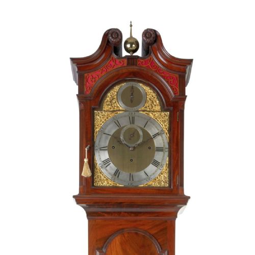 fig 4. An 18th-century Georgian mahogany longcase clock featuring an arched hood with a brass finial, a gilded brass dial, and a flame mahogany trunk door.