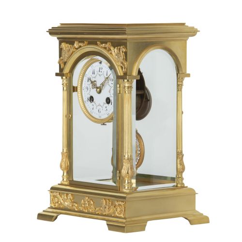 fig 1. An antique gilded brass four glass mantel clock featuring fluted corner columns, winged pegasus reliefs, an enamel dial, and a decorative pendulum with a portrait miniature.