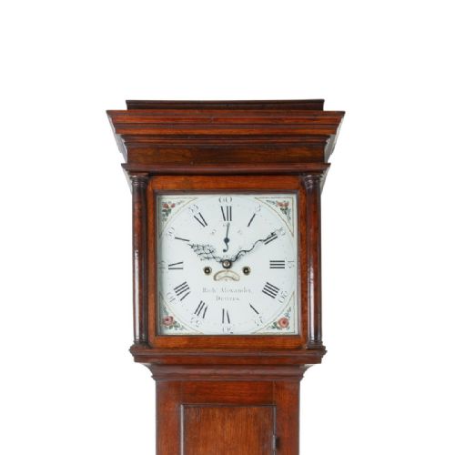fig 2. A tall Georgian oak longcase clock featuring a square painted dial, columned hood, and hinged trunk door.